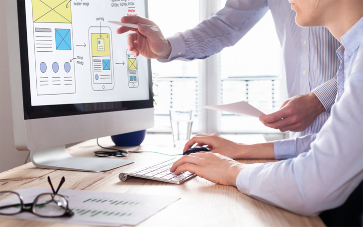 Duas pessoas projetam um site imobiliário no escritório