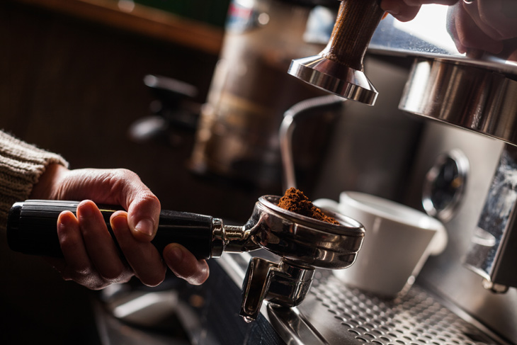 Un bărbat folosește un espressor