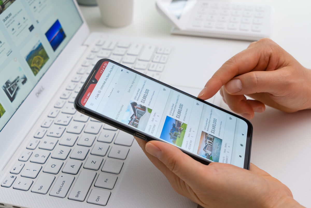 Homem navega no celular e um laptop