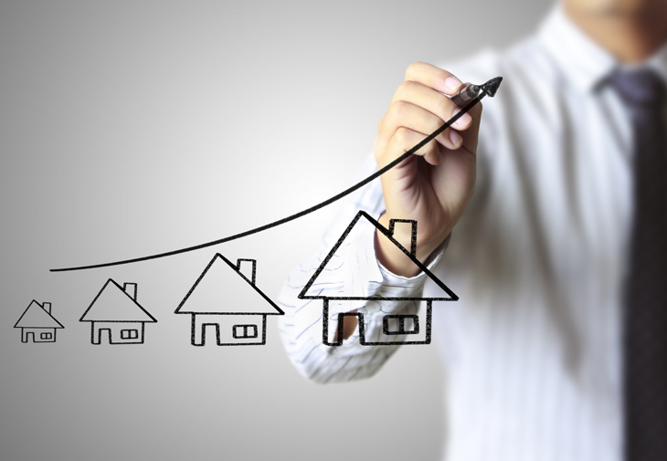 mężczyzna rysuje ceny domów na tablicy