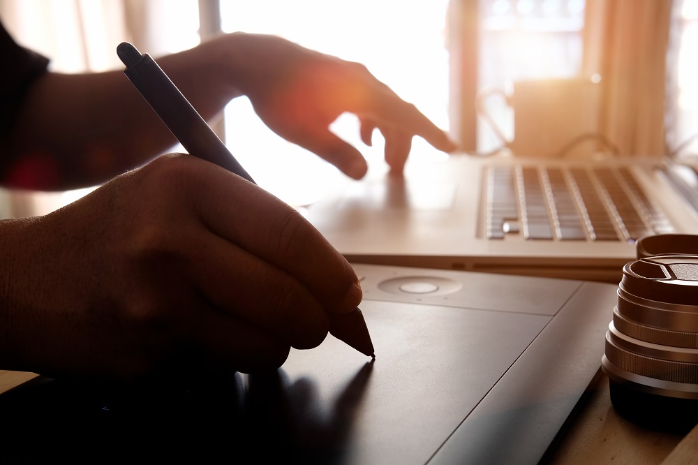 شخص يقوم بالرسم الرقمي على الكمبيوتر المحمول والكمبيوتر اللوحي