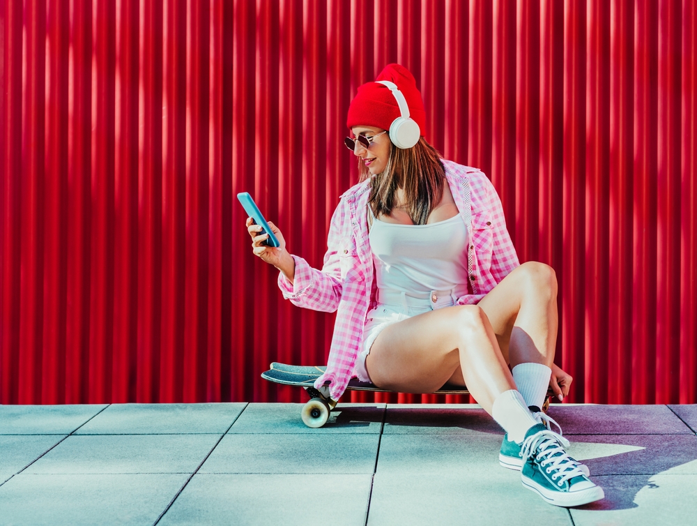 スケートボードで携帯電話を閲覧する女性