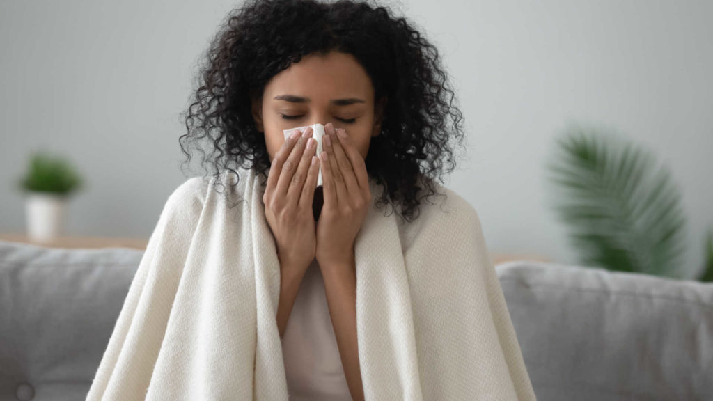 Una donna malata si soffia il naso a casa sul divano