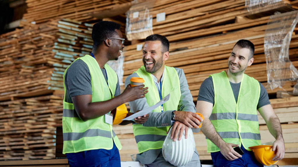 พนักงานโรงงานสามคนนั่งด้วยกันและหัวเราะ