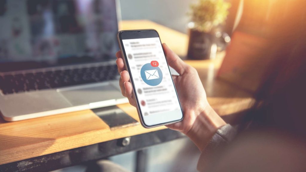 Изображение руки, держащей мобильный телефон с открытым приложением электронной почты