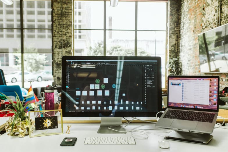 laptop z dodatkowym monitorem stoi na biurku z innymi drobiazgami