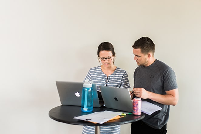 tata letak oleh roda gila menciptakan portofolio desain web yang lebih baik daripada pesaing pria dan wanita yang berdiri di meja tinggi dengan laptop