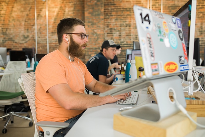 由飞轮开发团队结构角色在办公桌前工作的人与耳机在附近的办公桌上工作的团队成员的布局