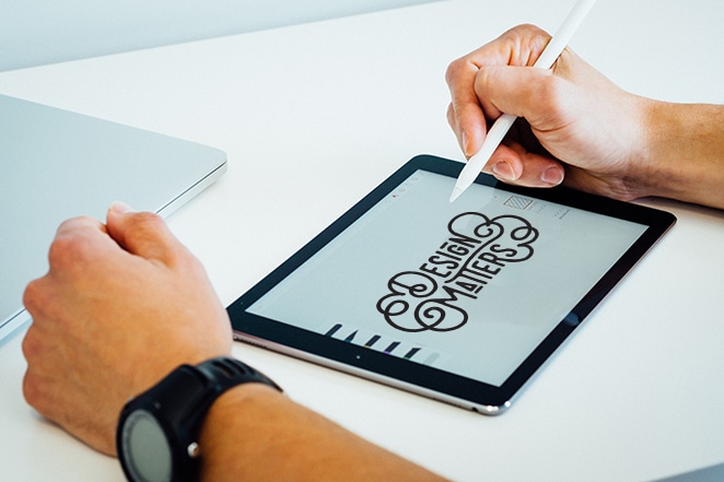 om care lucrează pe tabletă folosind stiloul. Tableta afișează tipografia „Design Matters”.