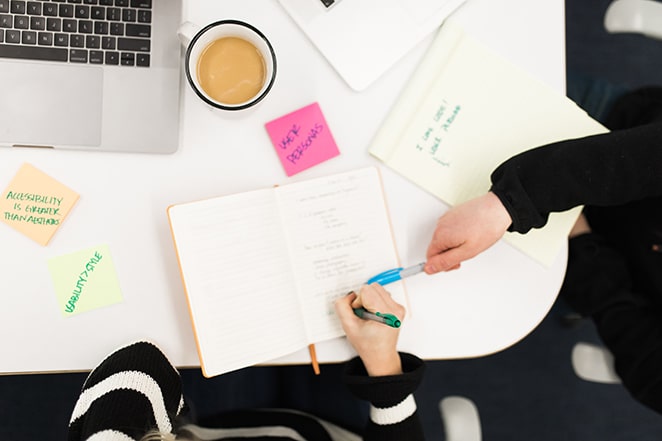 vedere de sus a oamenilor care lucrează la masă cu laptop și note