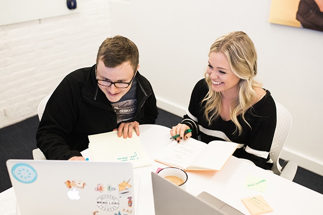 bărbat și femeie la masă cu laptop și notițe în timp ce planifică experiența utilizatorului pe un site bogat în date