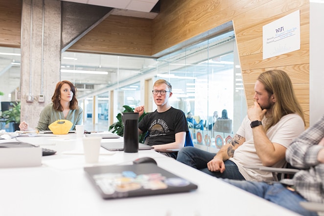 layout by flywheel dezvoltă o strategie de marketing pentru agenția de design cum să vorbesc doi bărbați și femei la masă lungă cu laptopuri și băuturi