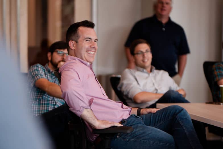 pria berbaju merah tersenyum saat bertemu dengan orang lain