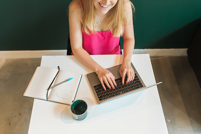 女性在筆記本電腦上寫內容營銷理念,附近有筆記本和飛輪杯