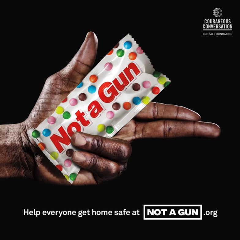 Immagine di una mano nera con in mano una caramella etichettata "Not a Gun" dalla premiata campagna pubblicitaria con lo stesso nome volta a sostenere la riduzione dell'escalation della polizia, l'addestramento alla non discriminazione e alla non violenza