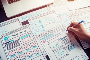 Diseñadores web que planifican las páginas de un sitio web utilizando wireframes de UX