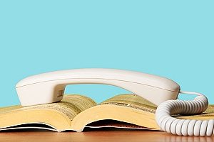 Gelbe Seiten mit mehreren Brancheneinträgen, auf denen sich ein Telefon befindet, über das der Benutzer eine Agentur für digitales Marketing anrufen will, um eine Strategie für digitales Marketing zu besprechen