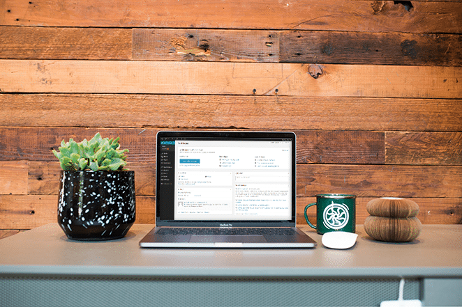 フライホイールによるレイアウトなぜワードプレスは2018年に最高のcmsであるか金属製の机の上のラップトップ画面で計画とマグカップが近くにあるワードプレス