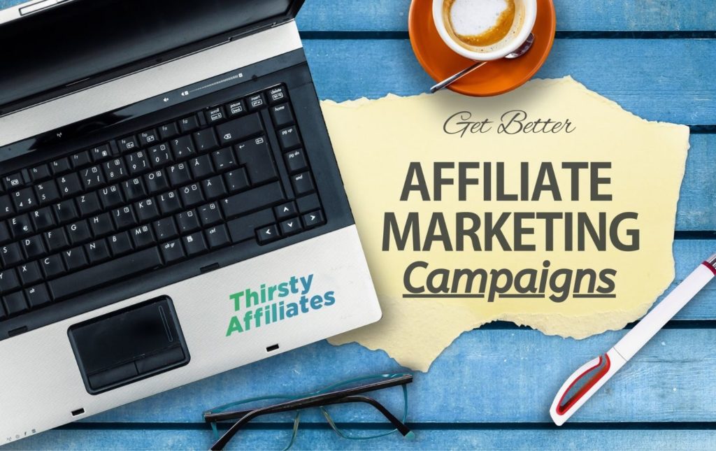 Textul spune „Obțineți campanii de marketing afiliate mai bune” în fața unui spațiu de lucru aglomerat. Logo-ul Thirsty Affiliates este prezent.